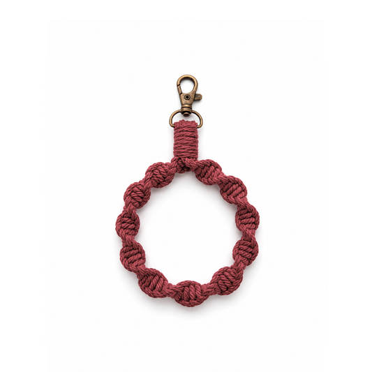 Gehaakt burgundy telefonkoord met vintage goudkleurige clip op witte achtergrond