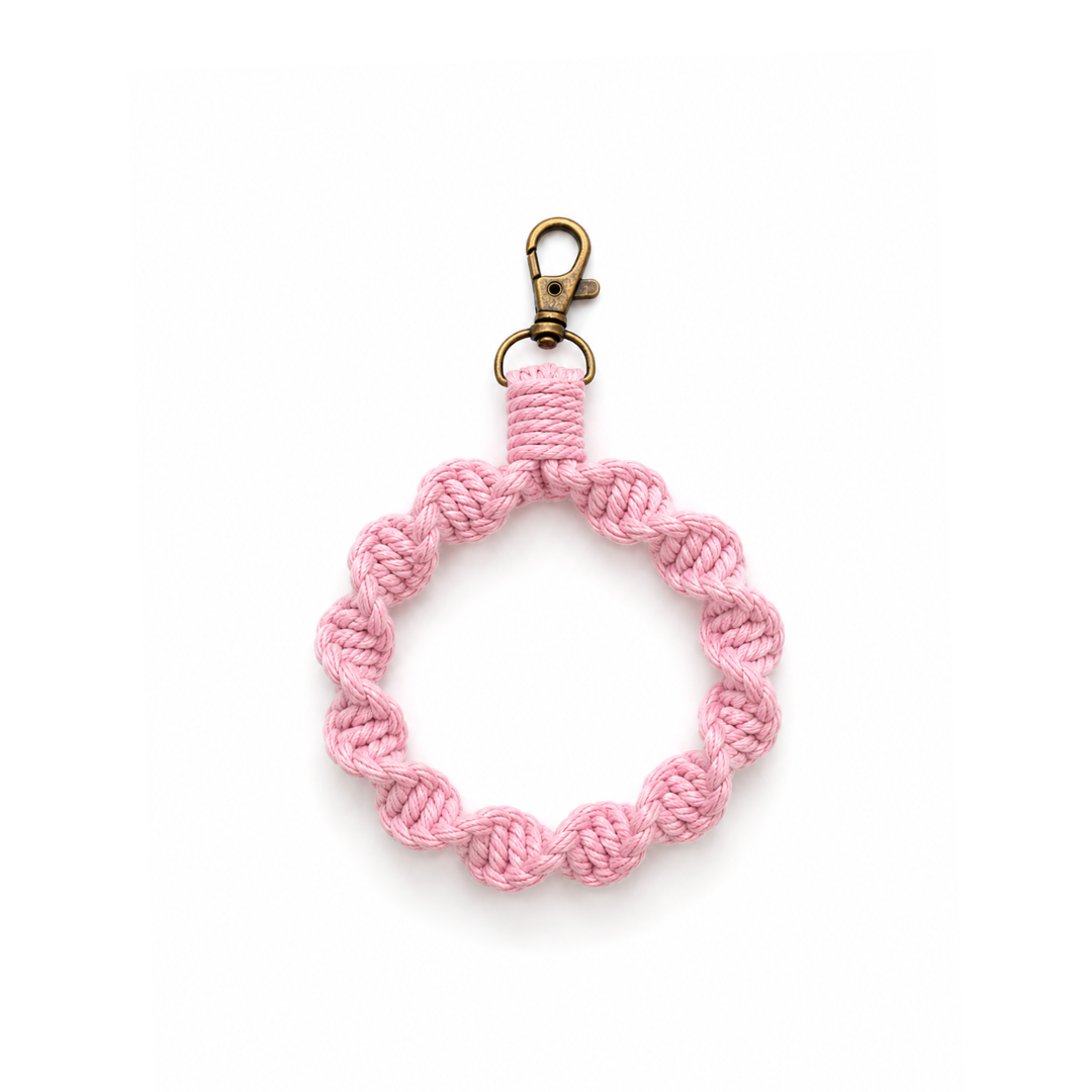 Gehaakt roze telefoonkoord met vintage goudkleurige clip op witte achtergrond