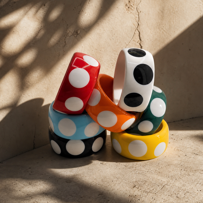 Stapel gekleurde polka dot bangles in rood, blauw, zwart, oranje, wit, groen en geel van Casa Jadel