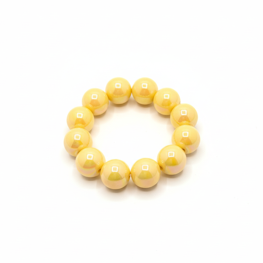 gele chunky kralenarmband met grote glanzende kralen op lichte achtergrond schuin