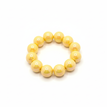 gele chunky kralenarmband met grote glanzende kralen op lichte achtergrond schuin
