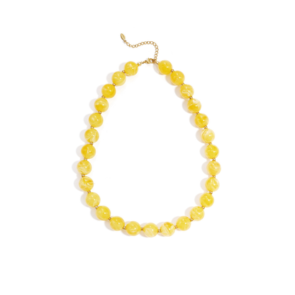 Gele gemarmerde kralenketting met goudkleurige accenten op lichte achtergrond.