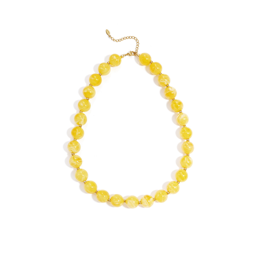Gele gemarmerde kralenketting met goudkleurige accenten op lichte achtergrond.