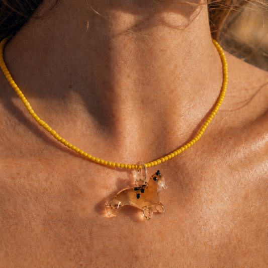 Model draagt gele kralenketting met zeehond bedel van Casa Jadel