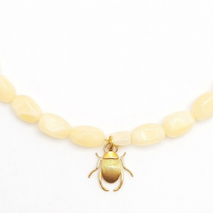 Inzoom lichtgele kralenketting met goudkleurige scarabee bedel in Ibiza style van Casa Jadel