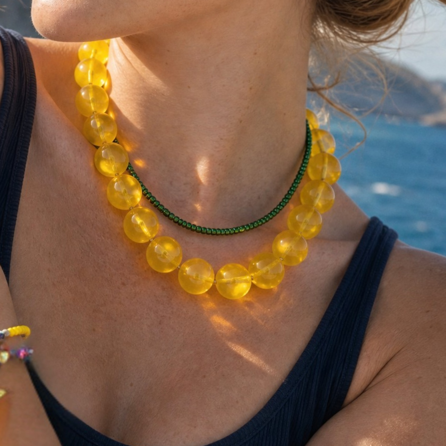 Model draagt een gele transparante kralenketting met fijne groene kralenketting in laagjes van Casa Jadel