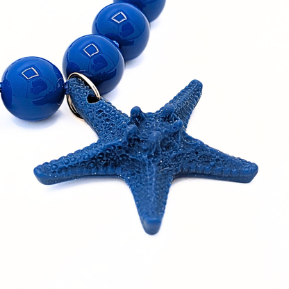 glanzende blauwe kralen met grote blauwe zeester op witte achtergrond