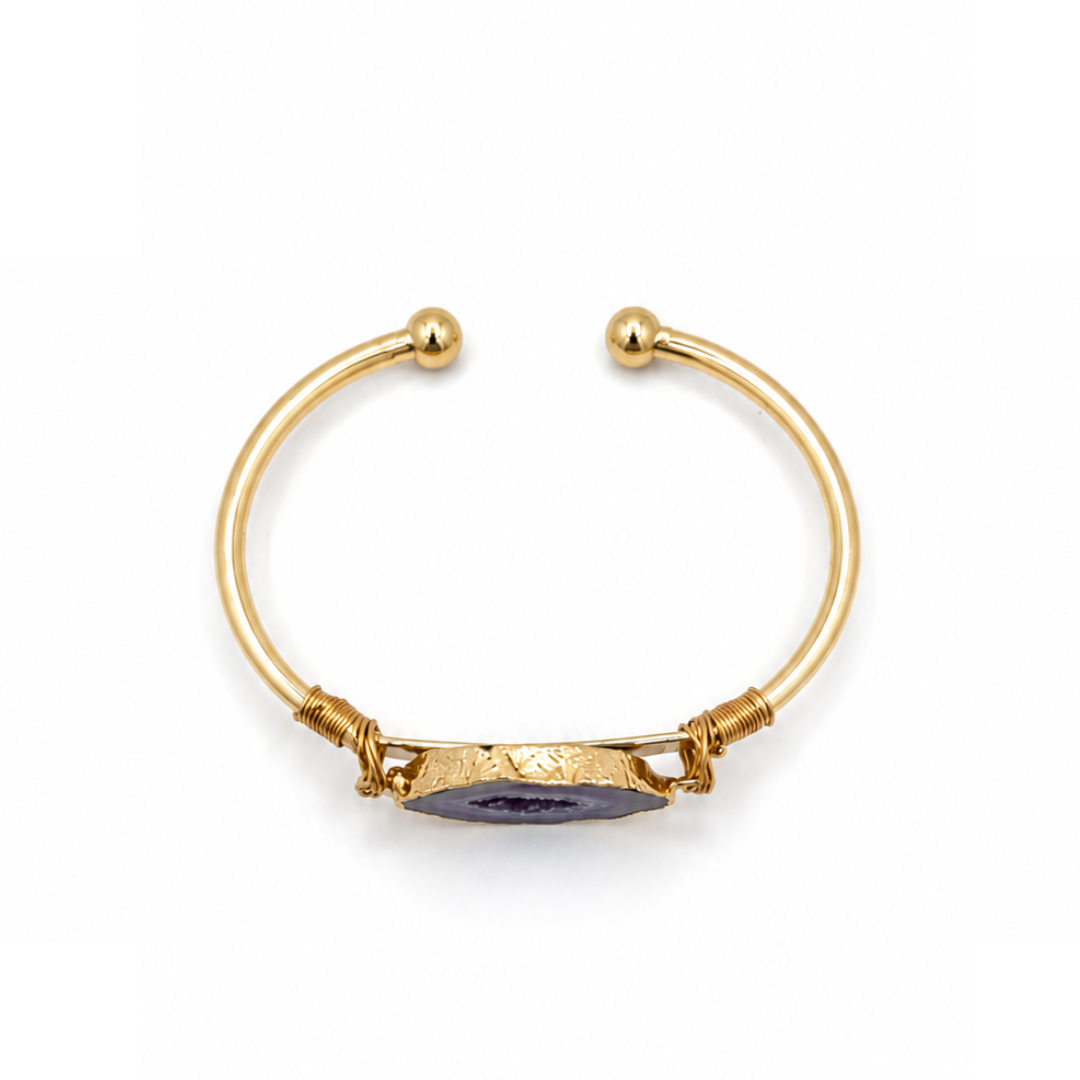Gouden bangle met paarse amethist natuursteen en luxe goudkleurige afwerking op witte achtergrond bovenaf