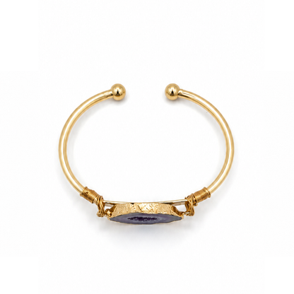 Gouden bangle met paarse amethist natuursteen en luxe goudkleurige afwerking op witte achtergrond bovenaf