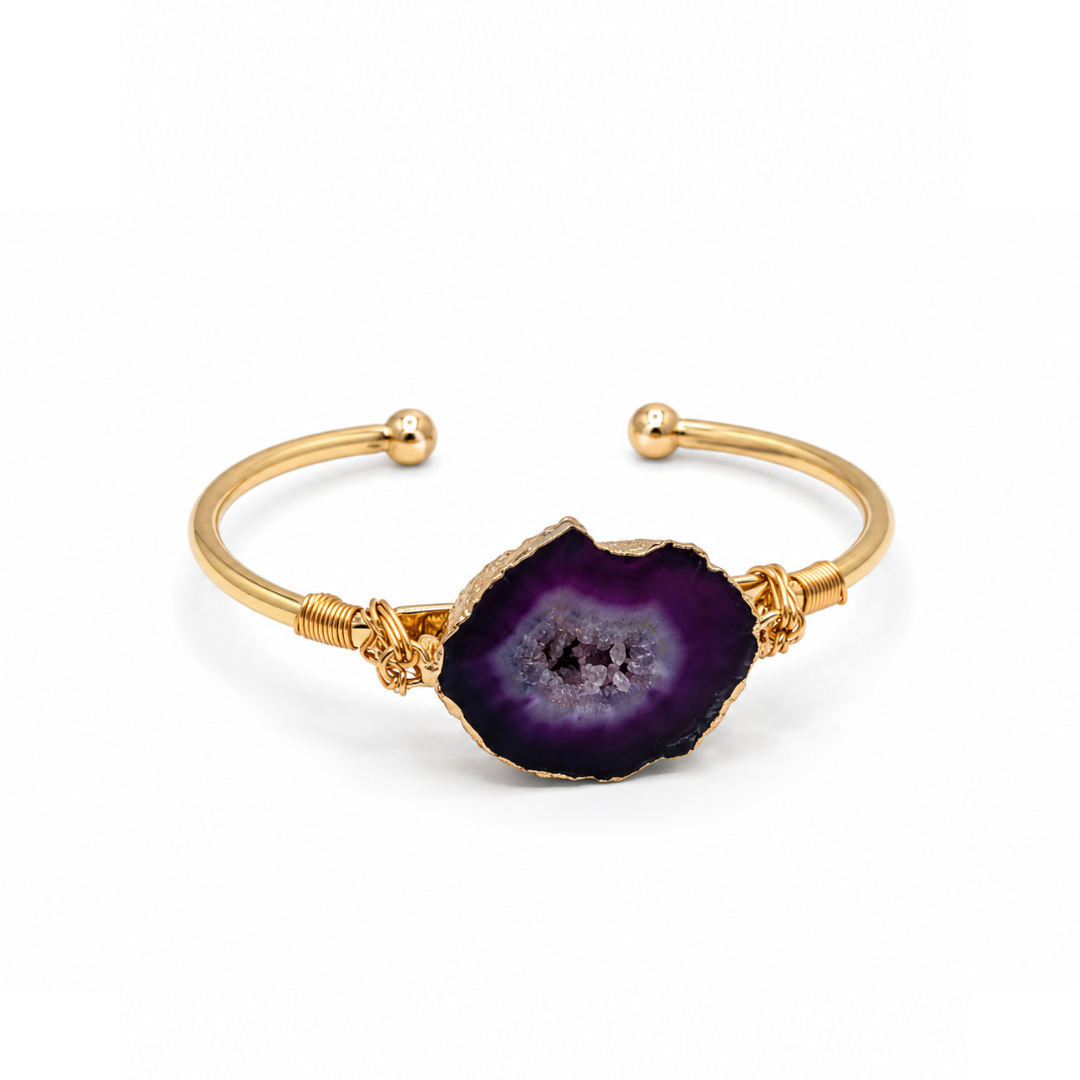 Gouden bangle met paarse amethist natuursteen en luxe goudkleurige afwerking op witte achtergrond schuin