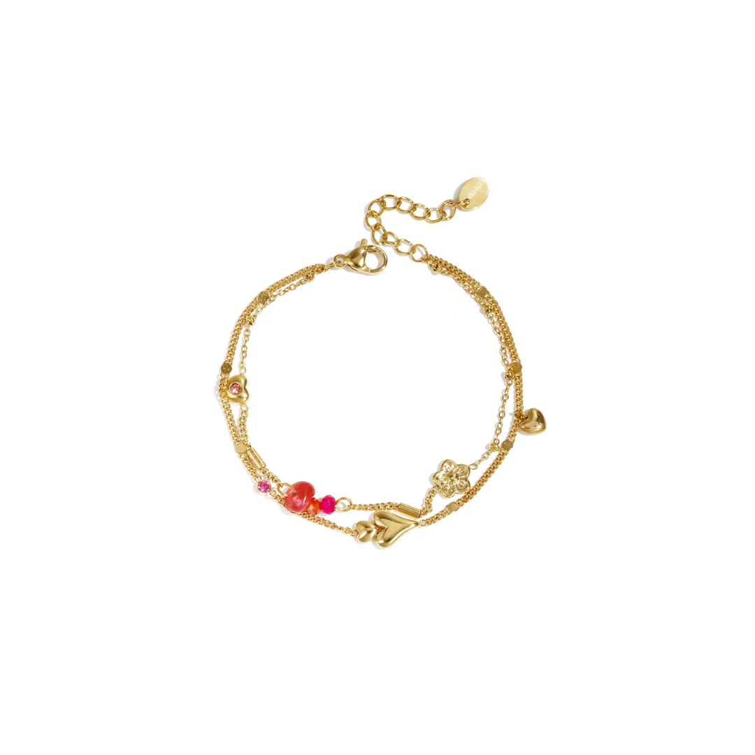 Gouden dubbele armband van stainless steel met hartjes, bloemetje en roze kralen.