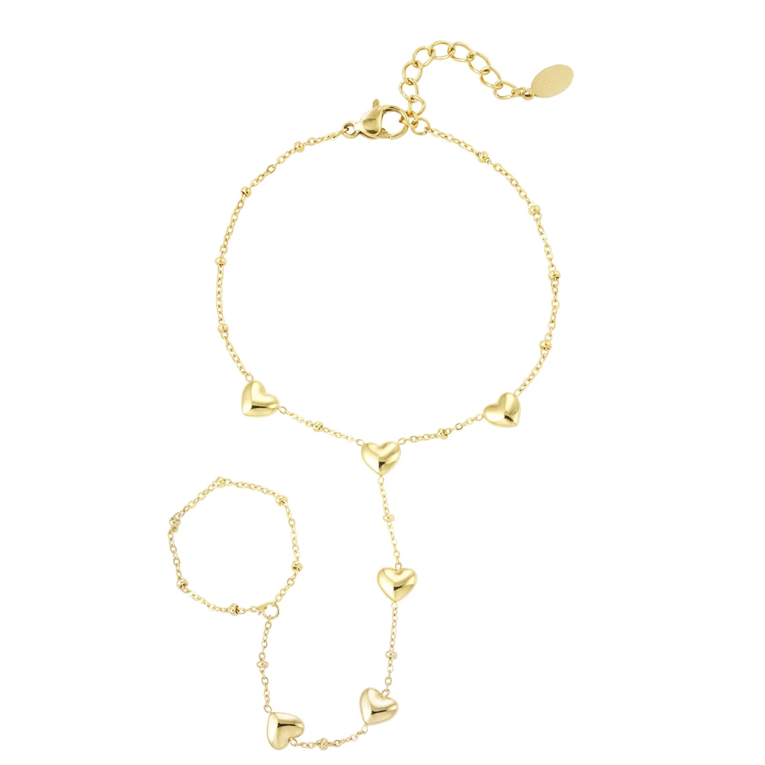 Gouden hand chain armband met ringdetail en glanzende hartjes bedels