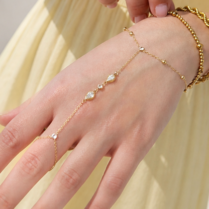 Gouden hand chain armband met ring en ovale steentjes verbonden met fijne schakels