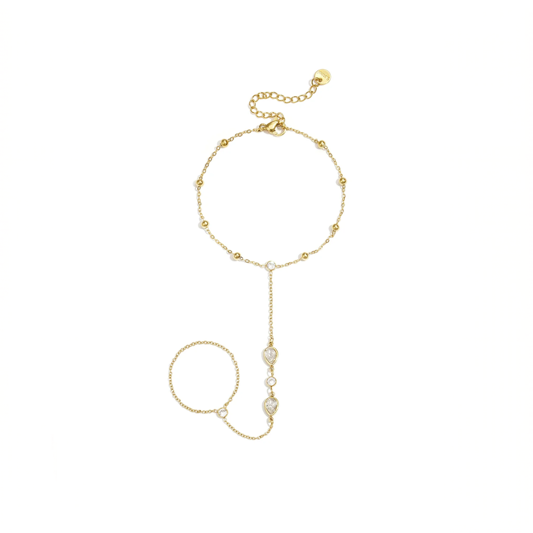 Gouden hand chain armband met ring en druppelvormige steentjes verbonden met fijne schakels