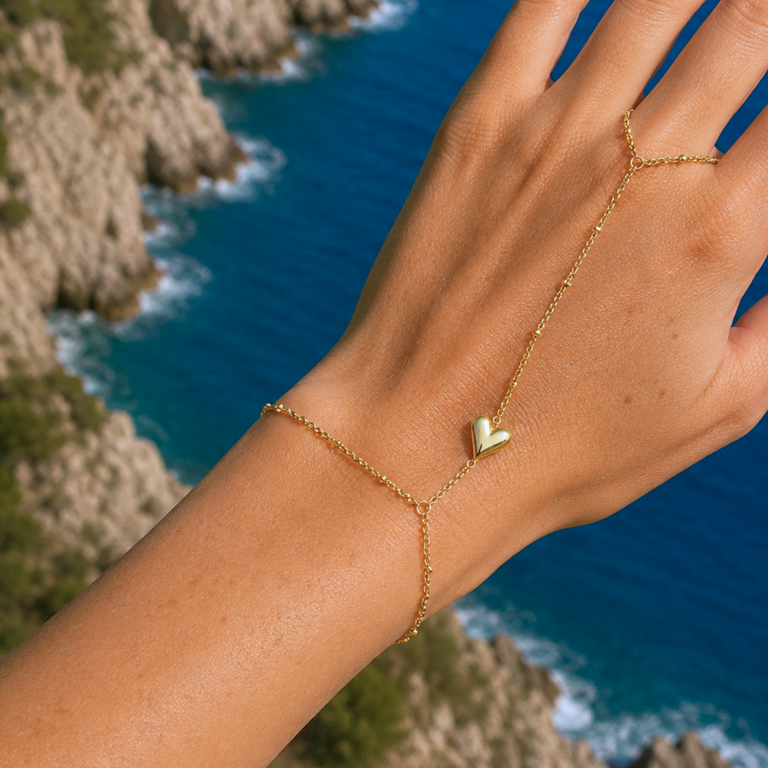 Gouden hand chain met dubbele armband, ring en hartje gedragen bij de zee.