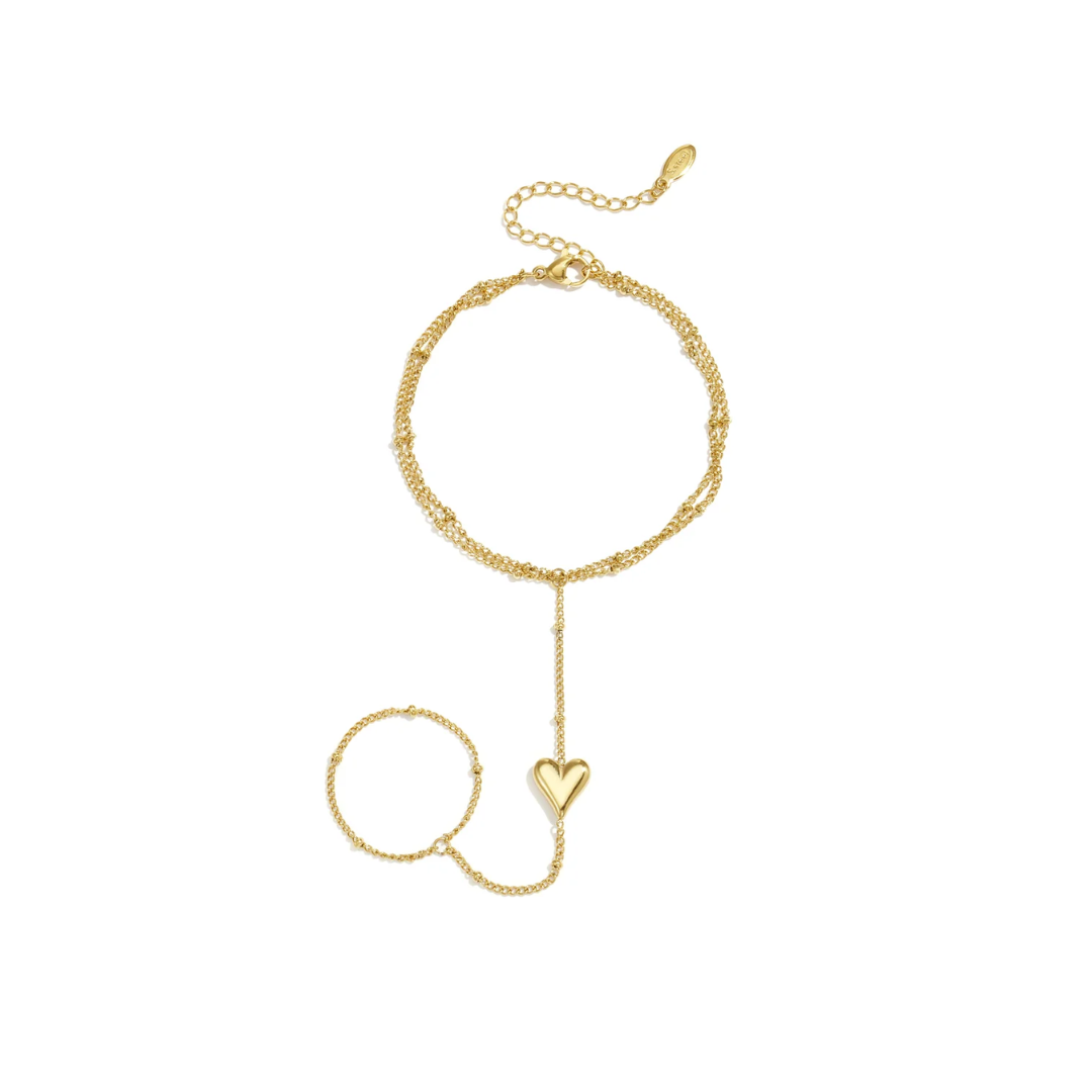 Gouden hand chain met dubbele armband, ring en hartje op witte achtergrond