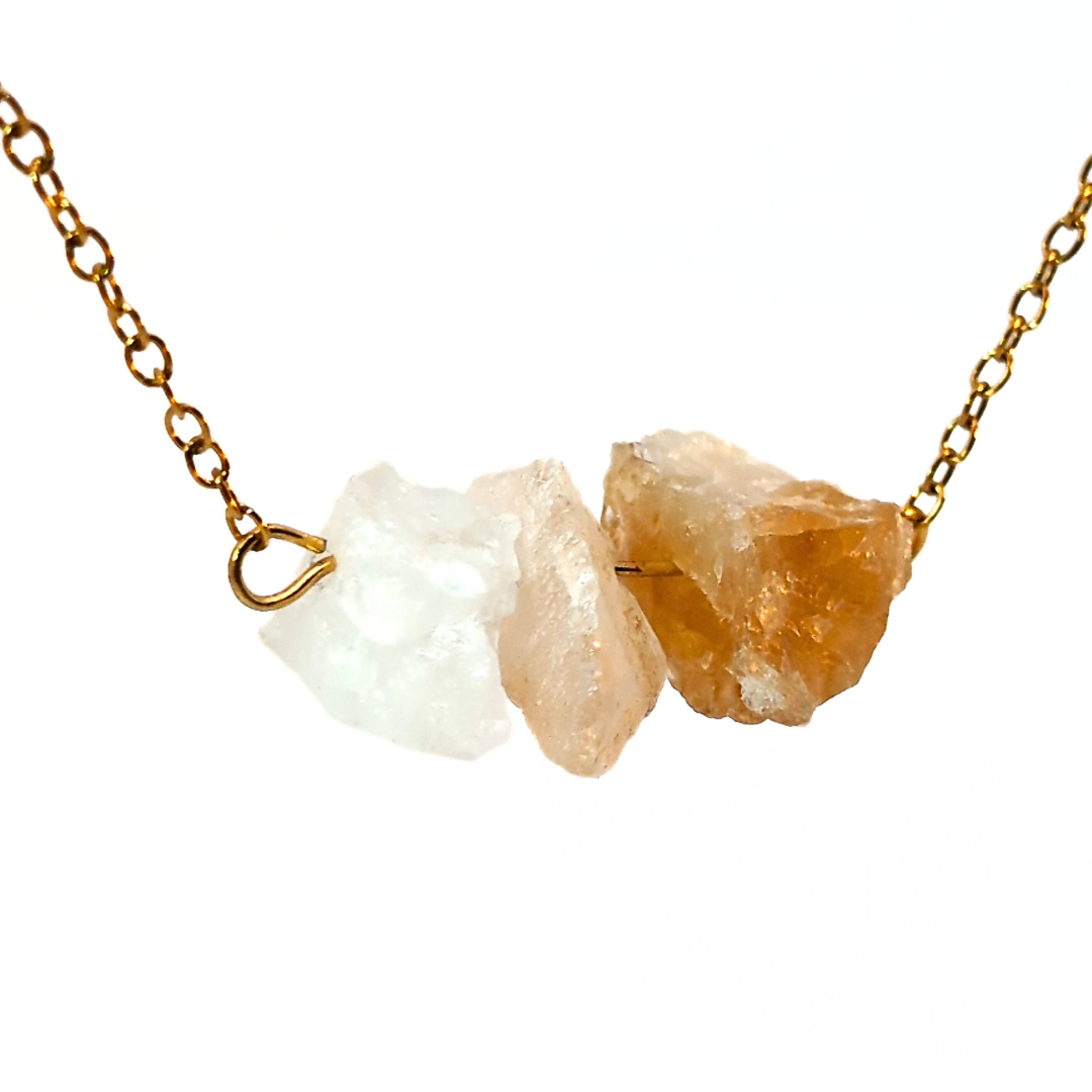 Close-up van gouden ketting met drie ruwe citrien edelstenen