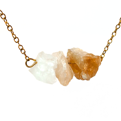 Close-up van gouden ketting met drie ruwe citrien edelstenen