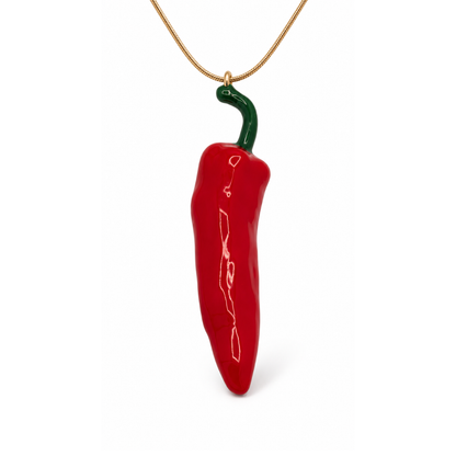 Close-up van een glanzende rode Spaanse peper hanger met groen gebogen steeltje aan een fijne goudkleurige ketting.
