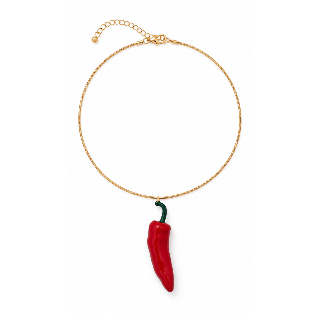 Gouden ketting met statement rode Spaanse peper hanger en verlengkettinkje op een witte achtergrond.