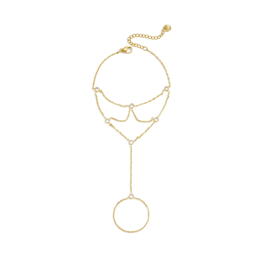 Gouden layered handchain armband met meerdere fijne schakelkettinkjes, heldere strass steentjes, een ronde vingerring en verstelbare sluiting.