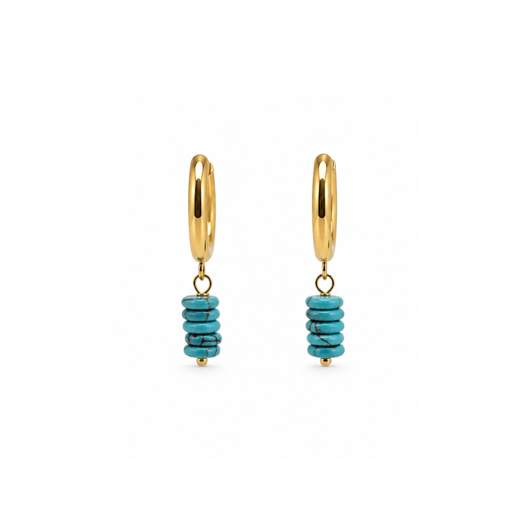 Gouden oorringen met turquoise natuursteen kralen en goudkleurige details op witte achtergrond