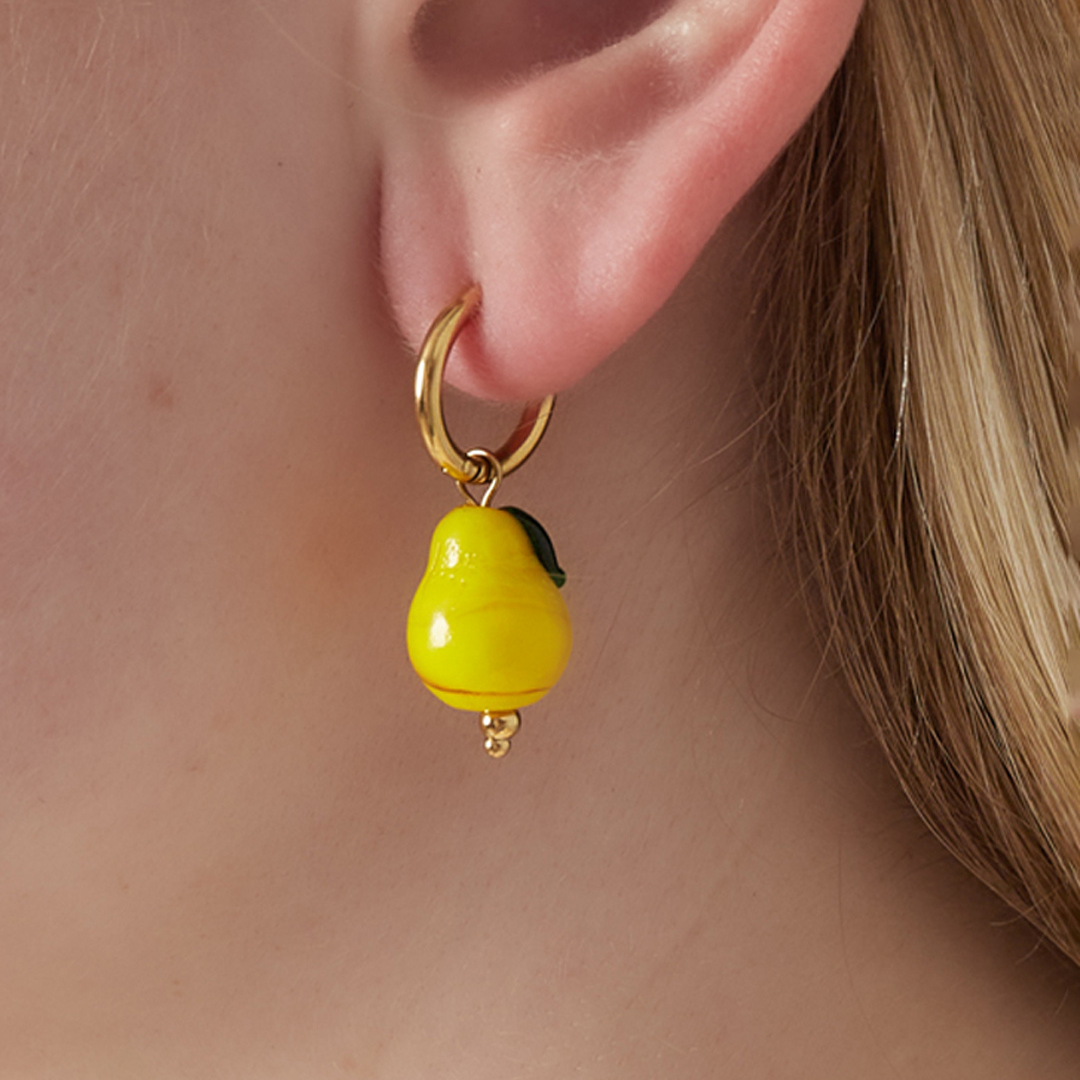 Gouden oorringetjes met groene peer hanger gedragen aan oor.