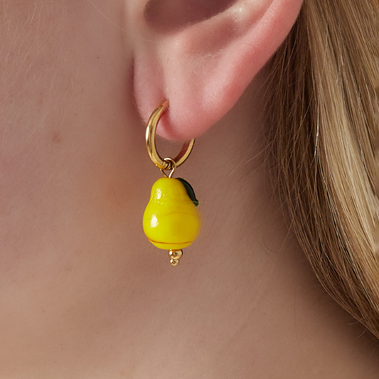 Gouden oorringetjes met groene peer hanger gedragen aan oor.