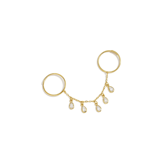 Gouden ring handchain met twee verbonden ringen, een fijne gouden schakelketting en vijf hangende druppelvormige strass bedels met heldere steentjes op witte achtergrond.