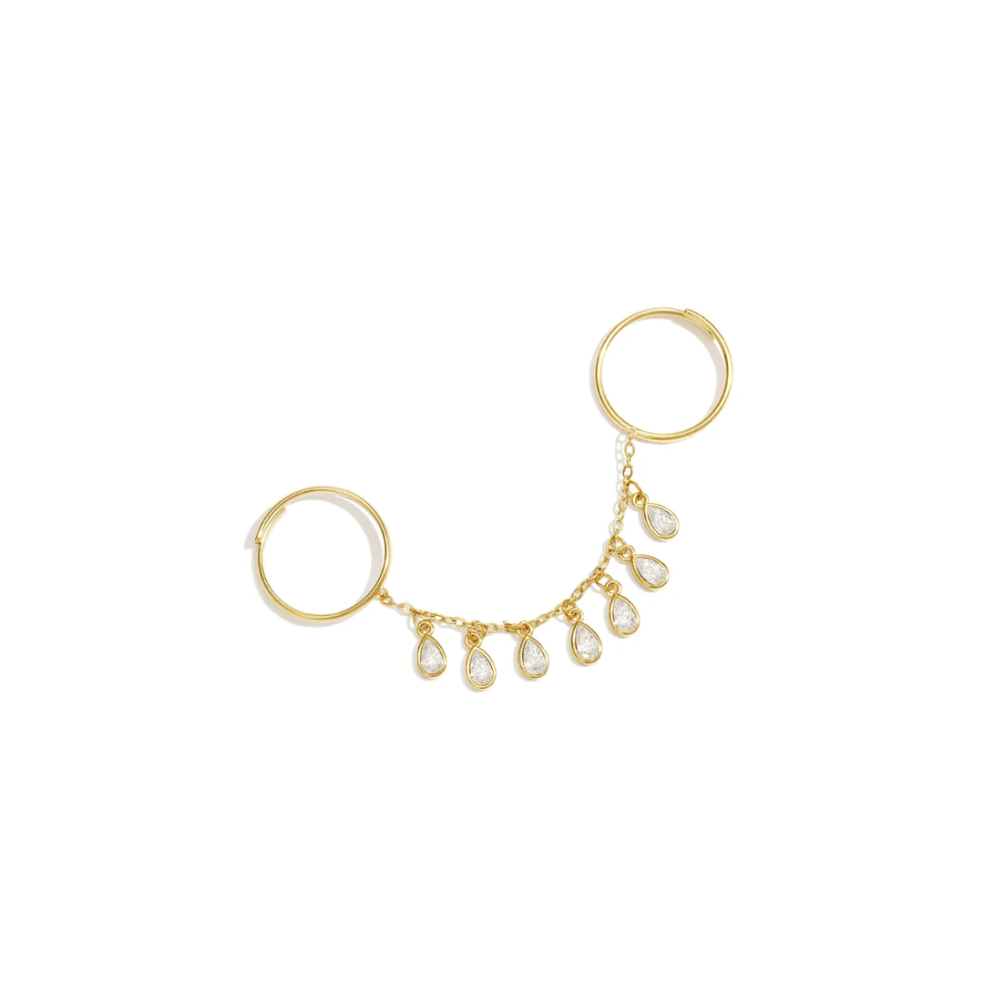 Gouden ring handchain met twee verbonden ringen, een fijne gouden schakelketting en zeven hangende druppelvormige bedels met heldere strass steentjes op witte achtergrond.