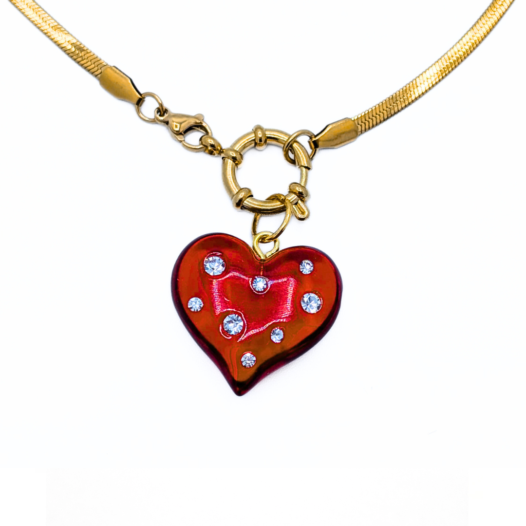 Detail van gouden snake ketting met ring sluiting en hart bedel