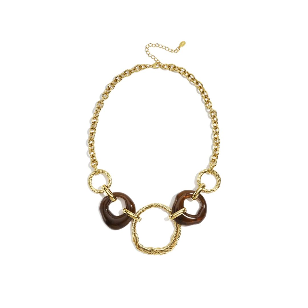 Gouden statement schakelketting met twee donkerbruine transparante turtoise ringen en grote gedraaide gouden middenring
