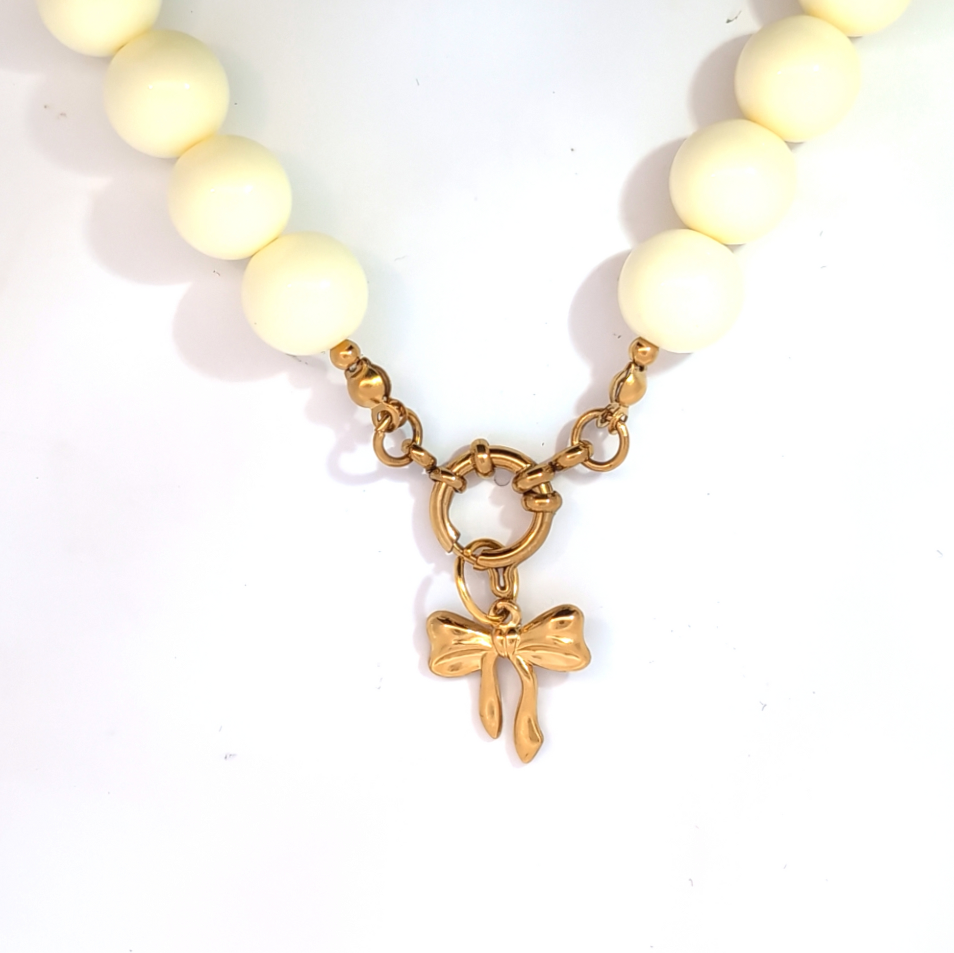 Gouden strik bedel gedragen aan kralenketting