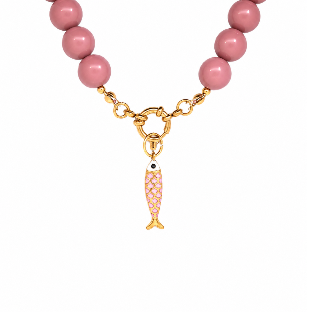 Gouden vis bedel met roze schubben hangend aan boeislot roze kralenketting Maud. 