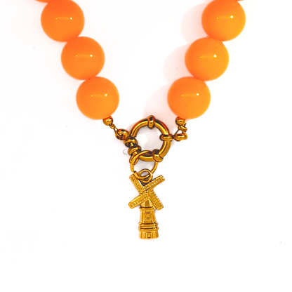 Gouden windmolen bedel gedragen aan een kralenketting met boeislot, Jadel sieraden.