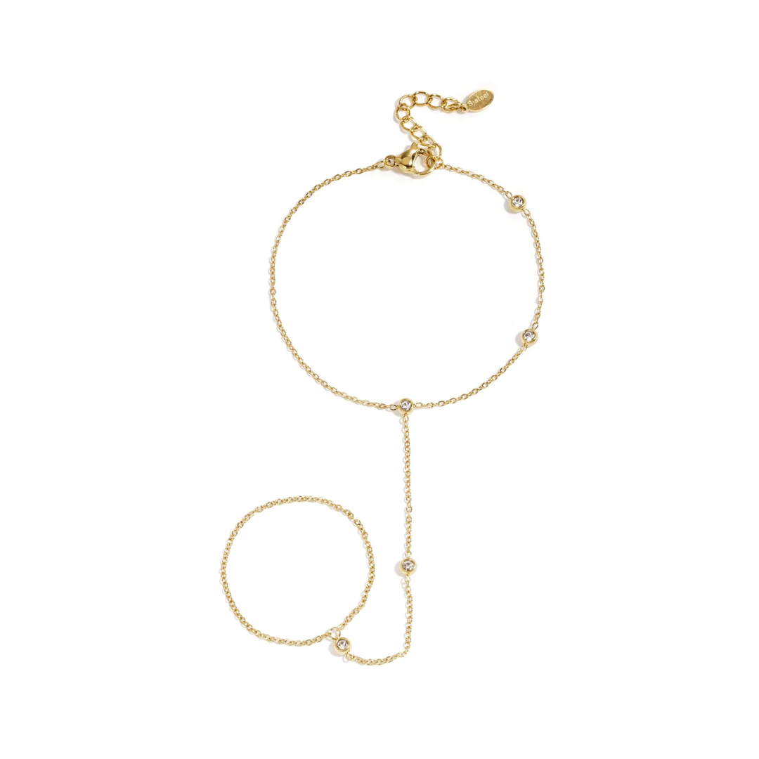 Goudkleurige asymmetrische hand chain met fijne ketting en strass steentjes op witte achtergrond
