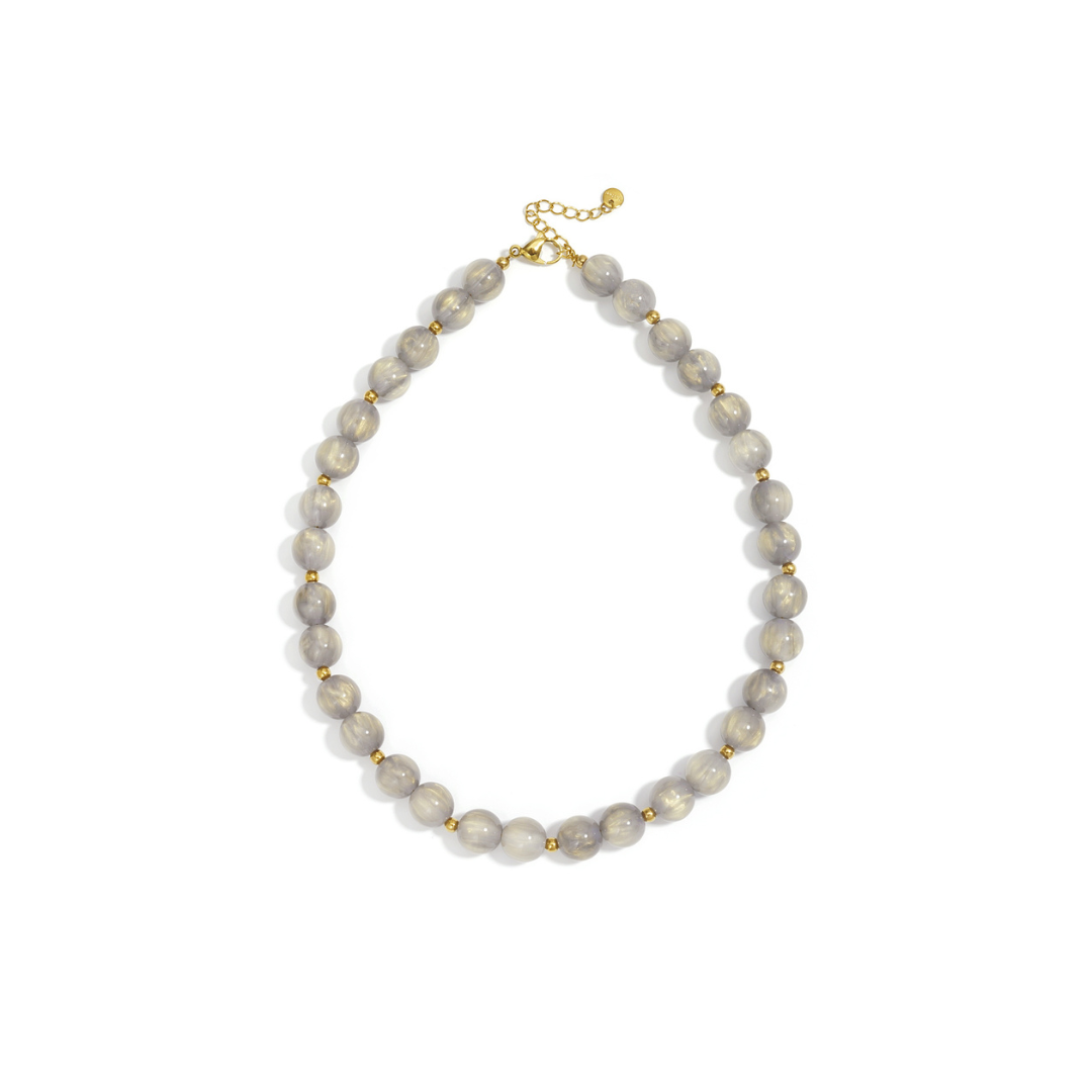 Taupe grijs goud gemarmerde kralenketting met goudkleurige accenten op lichte achtergrond.