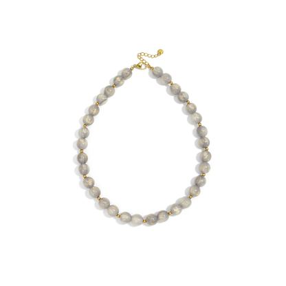 Taupe grijs goud gemarmerde kralenketting met goudkleurige accenten op lichte achtergrond.