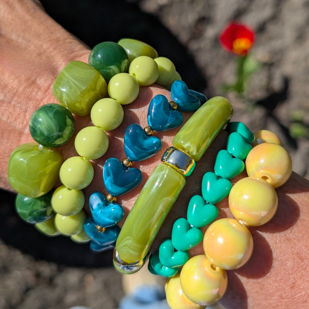 Arm met groene en gele armbanen marble en hartjes