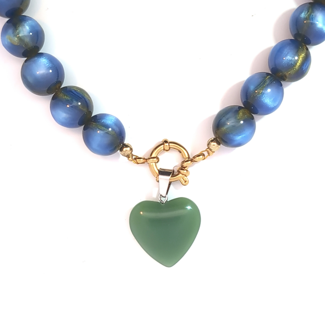 Groen hartje bedel met zilveren details gedragen aan blauwe kralenketting