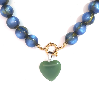 Groen hartje bedel met zilveren details gedragen aan blauwe kralenketting
