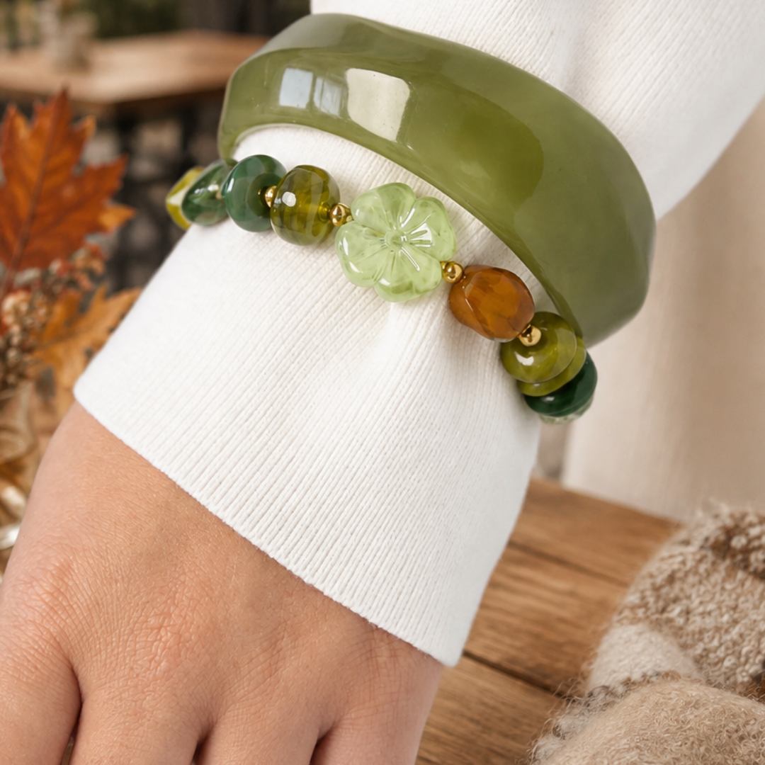 Arm met Groene chunky kralenarmband met gemixte kralen in groen en bruin, goudkleurige details en grote lichtgroene bloemkraal van Casa Jadel.