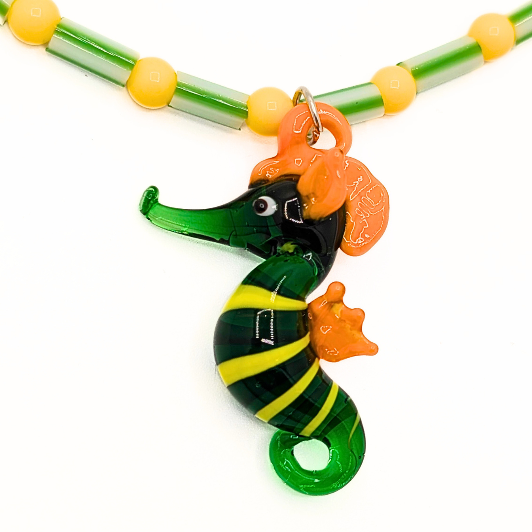 Detail van groene en gele kralenketting met zeepaardje bedel