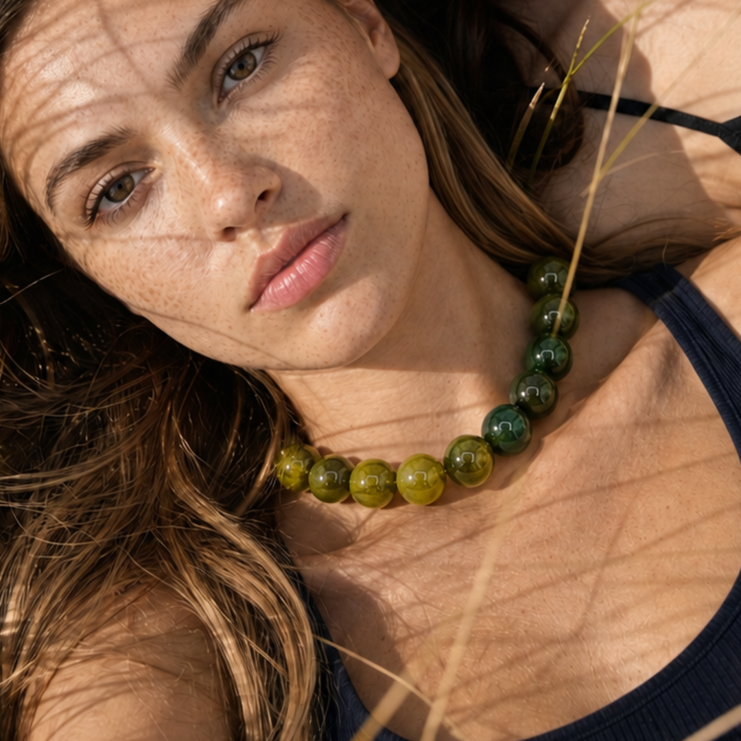Model draagt een groene grote kralenketting met glanzende ronde kralen van Casa Jadel