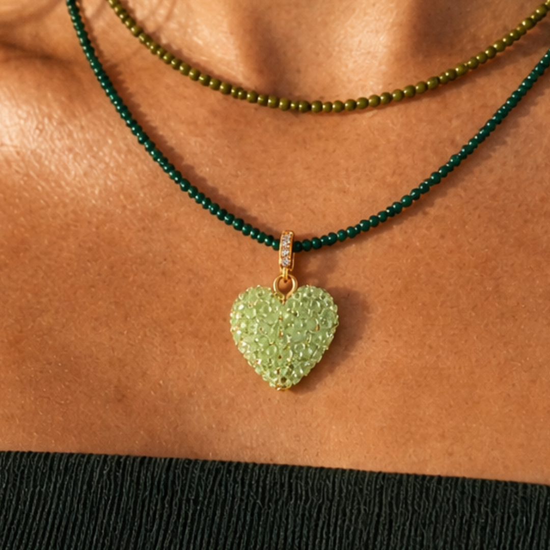 Model draagt een groene kralenketting met lichtgroene hart bedel en fijne groene kralenketting in laagjes van Casa Jadel

