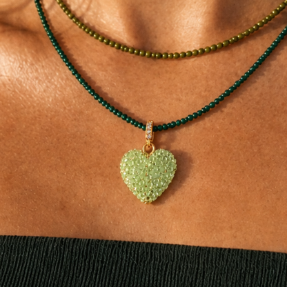 Model draagt een groene kralenketting met lichtgroene hart bedel en fijne groene kralenketting in laagjes van Casa Jadel
