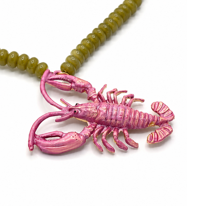 Close up van groene lange kralenketting met roze metallic kreeftbedel van Casa Jadel. 