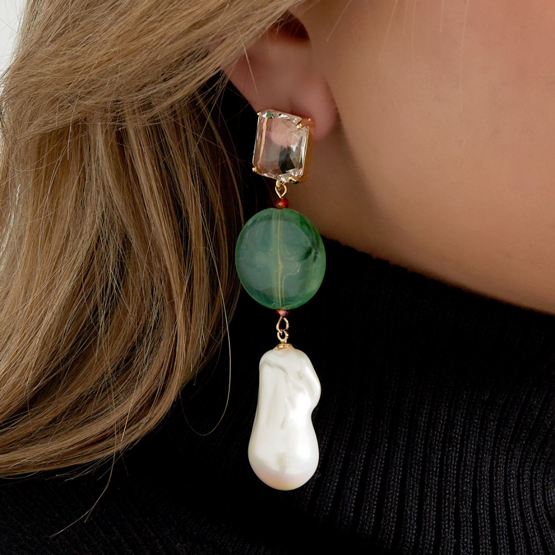 Groene oorhangers met facetgeslepen kristal en barok parel gedragen aan oor