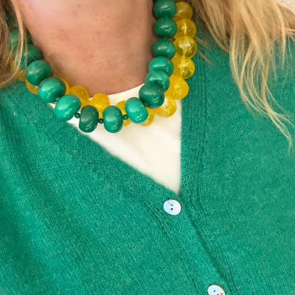model met wit tshirt en groen vest en groene ovale grote kralen ketting en een gele ovale grote kralen ketting
