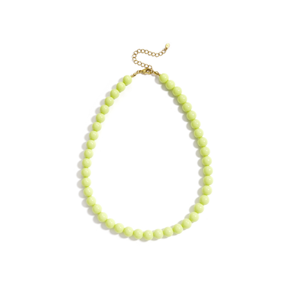 Limegroene kralenketting met ronde glanzende kralen en goudkleurige sluiting op witte achtergrond